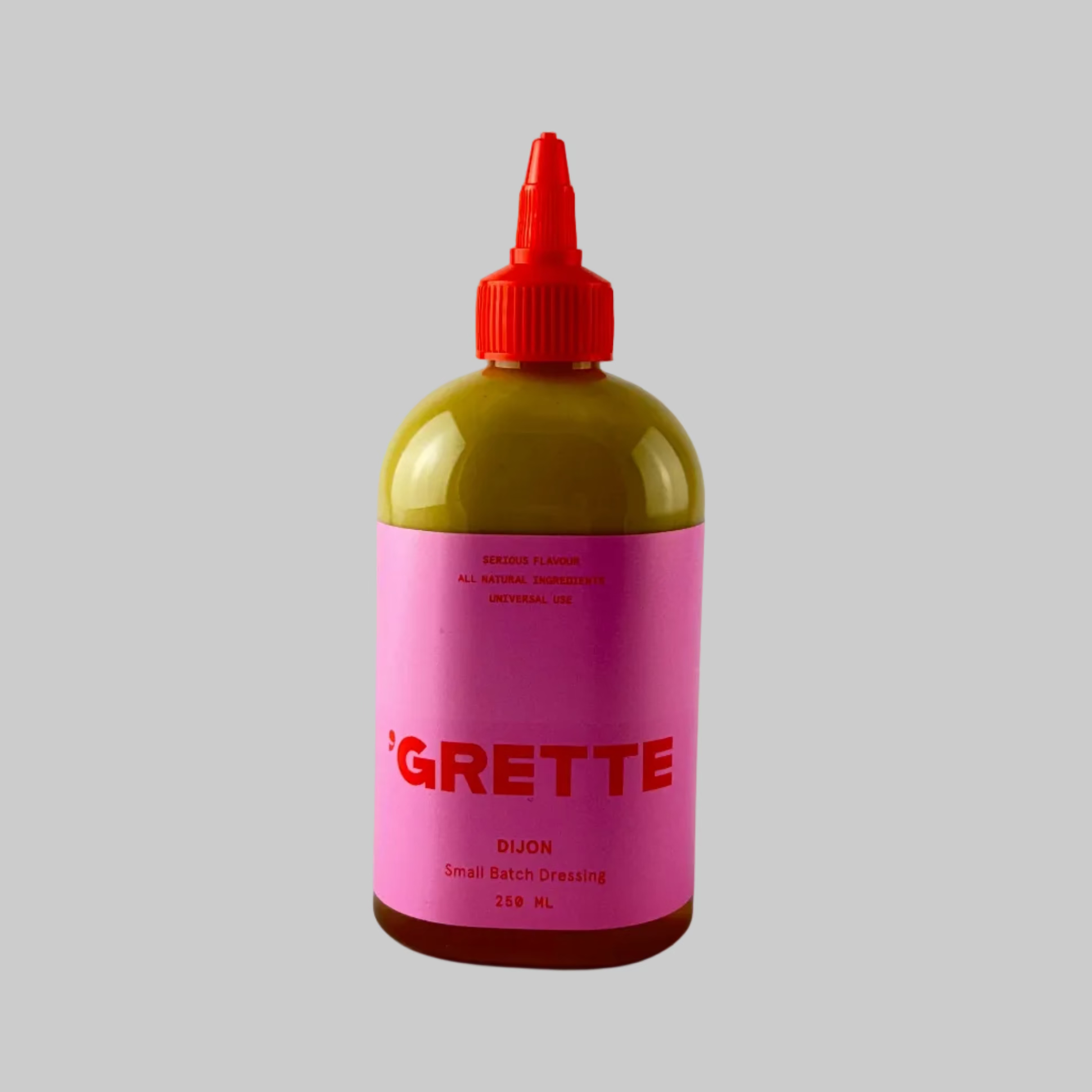 Bottle of dijon dressing from Grette with a pink label on a grey background