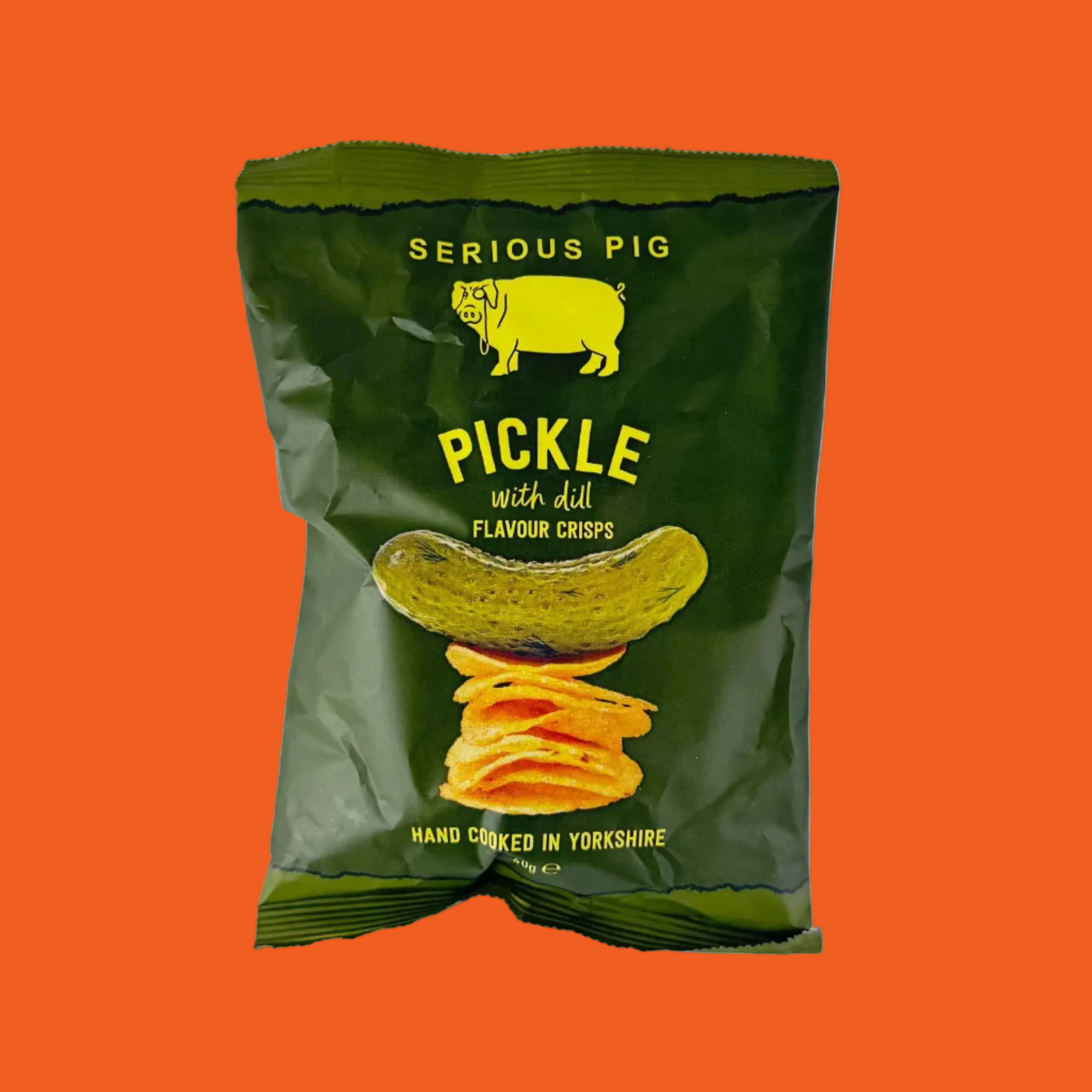Green packet of 'Serious Pig' pickle with dill flavor crisps on a orange background